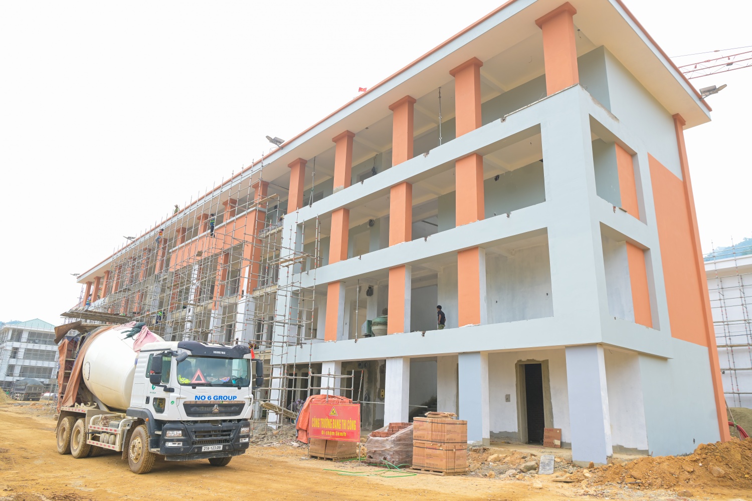 Hiện tại, 10/10 hạng mục chính đã hoàn thành phần thô và đang bước vào giai đoạn hoàn thiện. Trong đó, 4 khối nhà cơ bản hoàn thiện, đang tiến hành sơn và lắp đặt thiết bị; 6 khối nhà còn lại đạt khoảng 75% khối lượng hoàn thiện. Các hạng mục phụ trợ như san nền đã hoàn tất, hệ thống kè đạt khoảng 80%, nhiều hạng mục hạ tầng kỹ thuật khác đạt từ 60% khối lượng. Dự kiến đến giữa tháng 5/2026 sẽ cơ bản hoàn thành phần xây dựng chính và tiếp tục hoàn thiện, lắp đặt thiết bị trong tháng 6/2026.