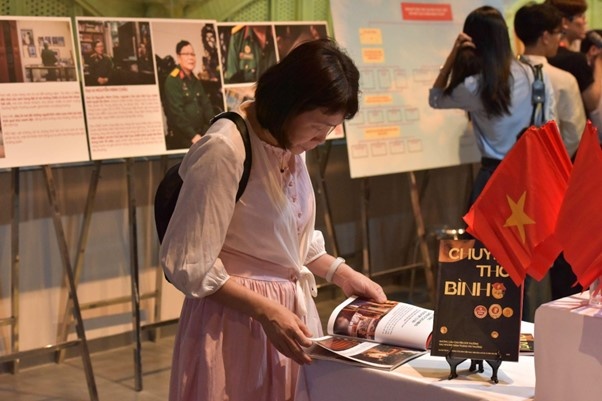 Khách tham quan chăm chú theo dõi photobook “Chuyện thời bình”