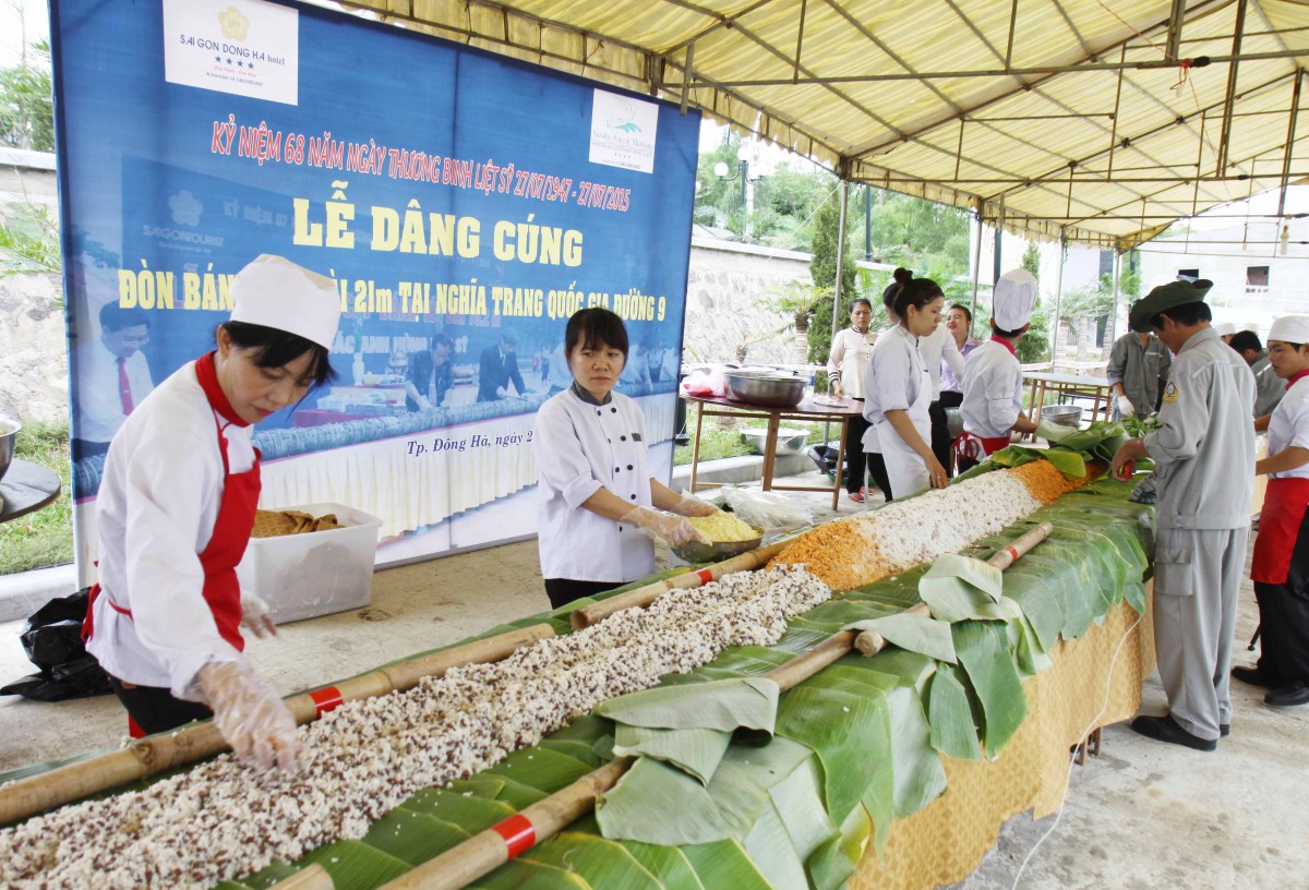 Nhân kỷ niệm 68 năm Ngày Thương binh - Liệt sỹ (27/7/1947 - 27/7/2015), ngày 22/7, Khách sạn Sài Gòn - Đông Hà tổ chức gói đòn bánh tét để dâng cúng tri ân các liệt sỹ tại Nghĩa trang liệt sỹ quốc gia Đường 9 (Quảng Trị). Đòn bánh tét có chiều dài 21 mét, đường kính 0,2 mét, được gói bằng các nguyên liệu: gạo nếp, thịt lợn, đậu đỗ các loại và nhiều loại gia vị. Trong ảnh: Nhân viên Khách sạn Sài Gòn - Đông Hà gói bánh tét. Ảnh: Hồ Cầu-TTXVN